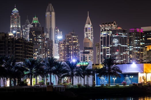 Dynamic night view of Dubai's skyline with illuminated skyscrapers and palm trees.