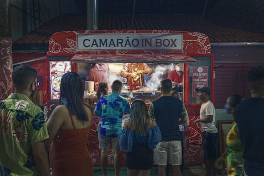 Crowds gather at a shrimp food truck in Porto de Galinhas for nighttime street food delight.