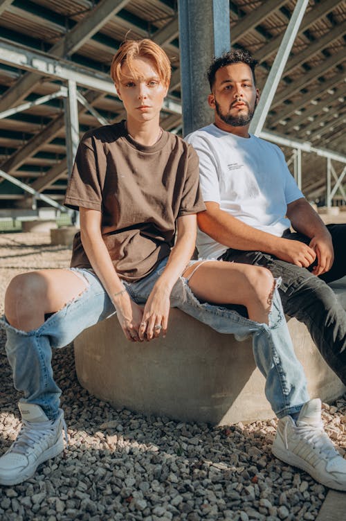 Two Stylish People seated on a Concrete Surface 