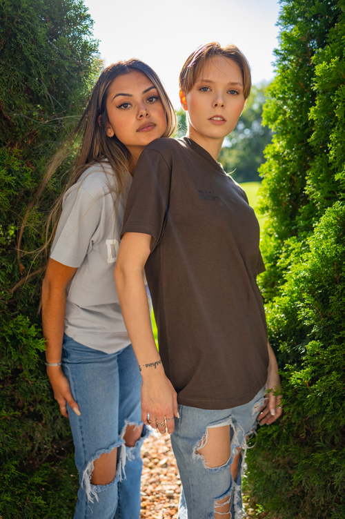 Free Two young women posing outdoors wearing casual, stylish outfits with tattered jeans. Stock Photo
