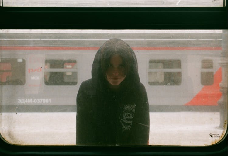 Hooded Unrecognizable Young Person Standing On Platform At Train Window