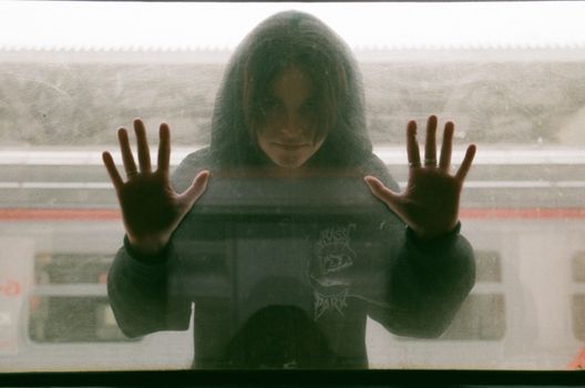 Teenage Girl in Black Hooded Blouse Looking Through Train Window