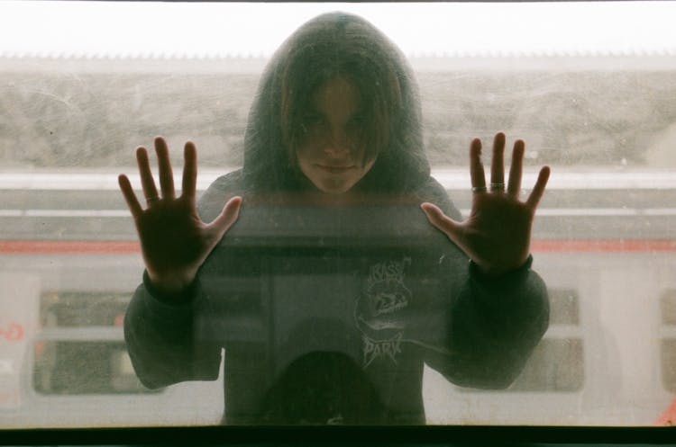 Teenage Girl In Black Hooded Blouse Looking Through Train Window