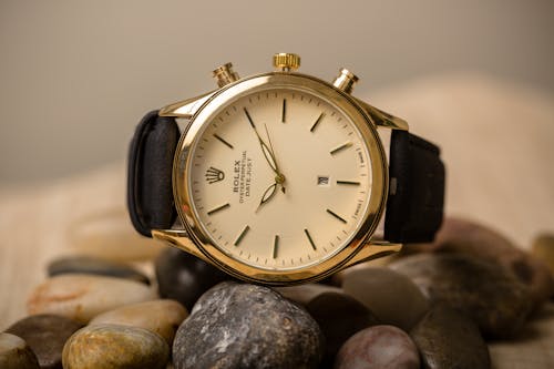 Free Rolex Wristwatch with Black Straps on Top of Pebbles Stock Photo