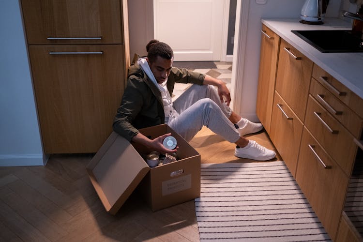 A Man Looking The Canned Food In The Box