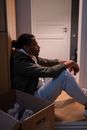 A Man Sitting on the Floor beside a Cardboard Box