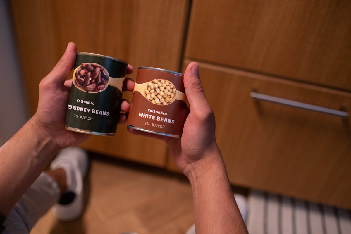 Person organizing emergency food supplies in kitchen pantry with labeled containers