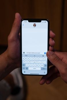 Close-up of hands holding a smartphone displaying a messaging app.