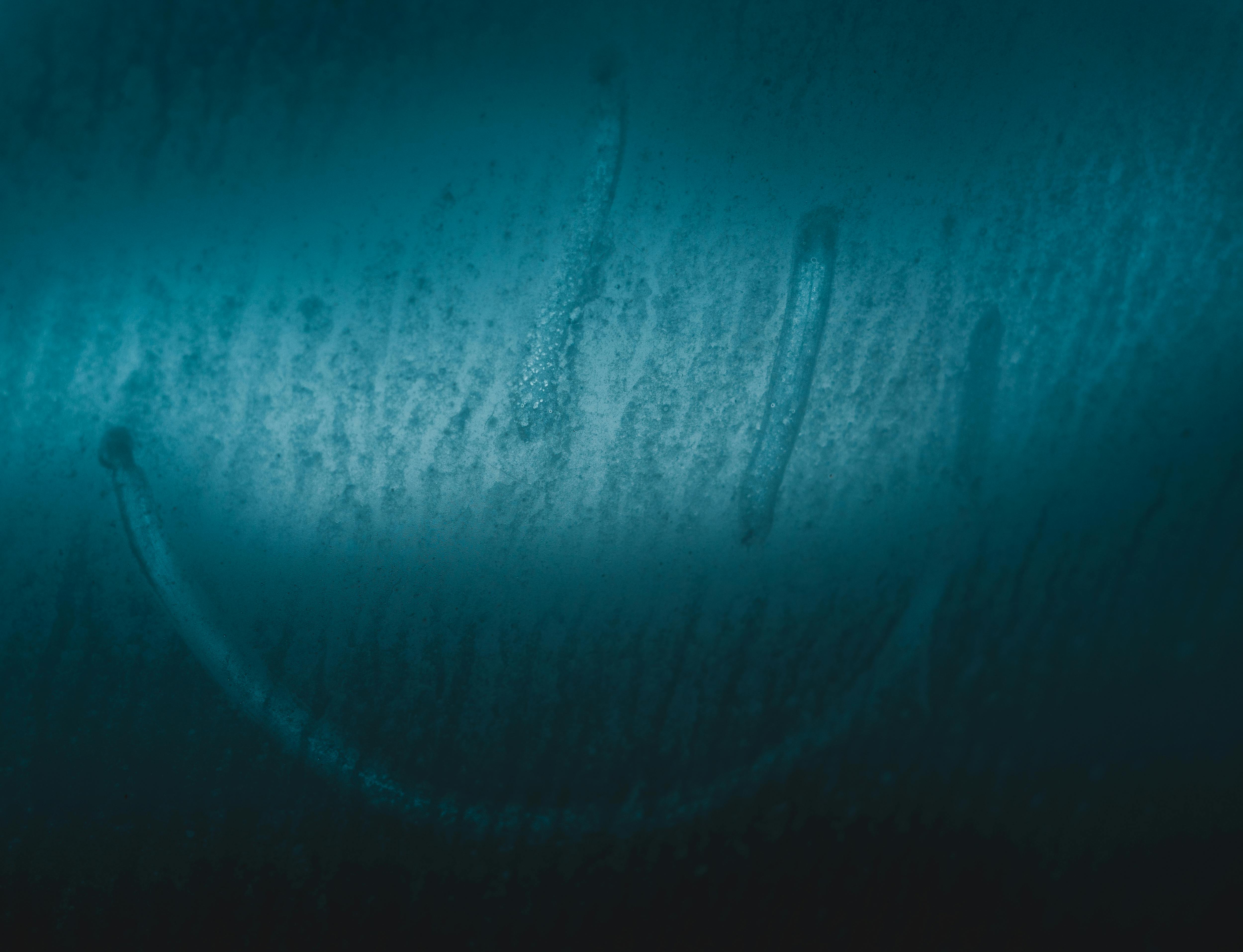 A smiley face drawn on a foggy glass surface with a blue tint, evoking emotion.