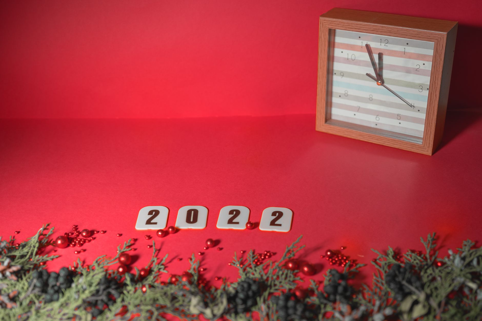 Festive 2022 New Year setup with a clock and holiday decorations on a vibrant red background.
