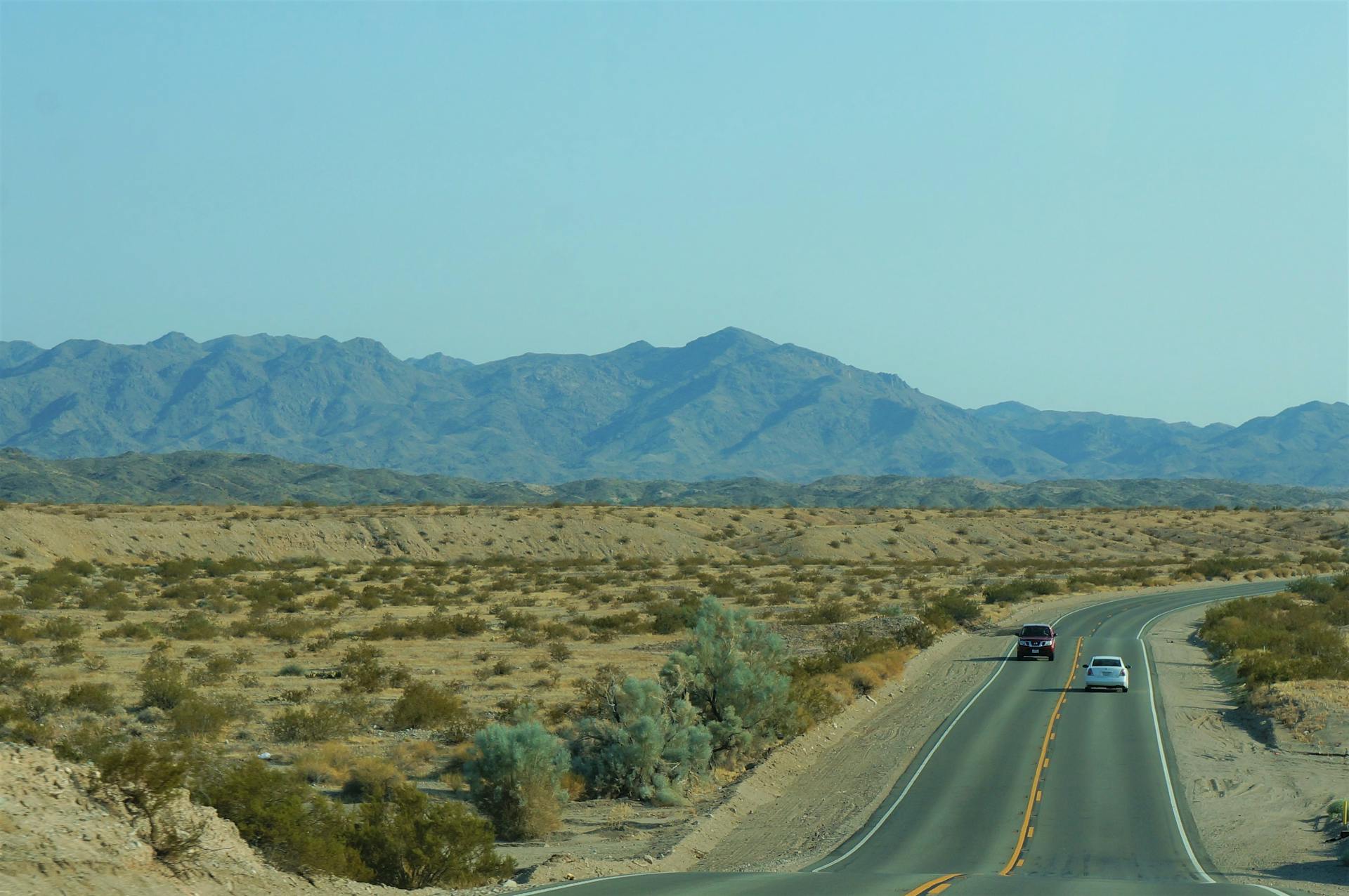 Explore the vast desert roads of California with distant mountain views.