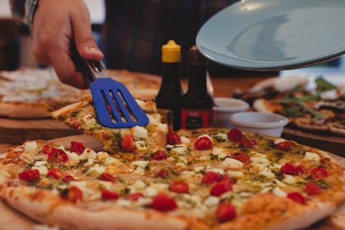 Close-Up Shot of a Person Getting a Slice of Delicious Pizza