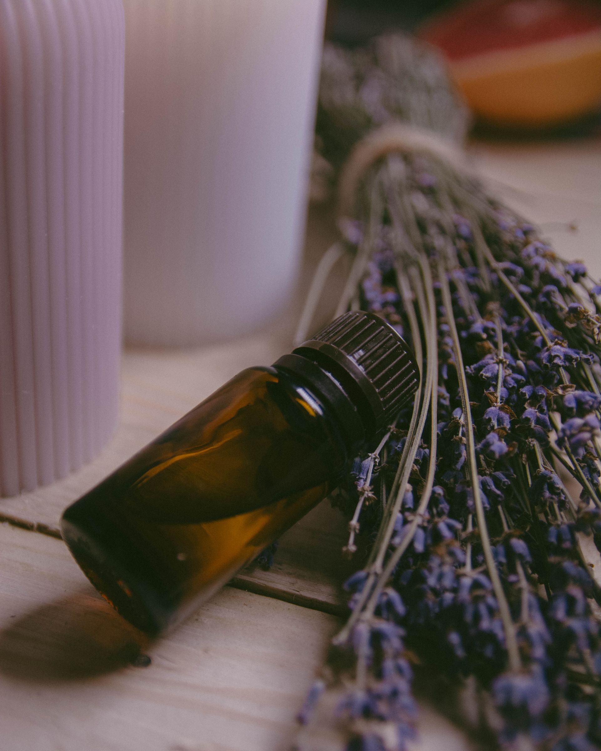 Botella de aceite esencial con ramo de lavanda y velas sobre madera