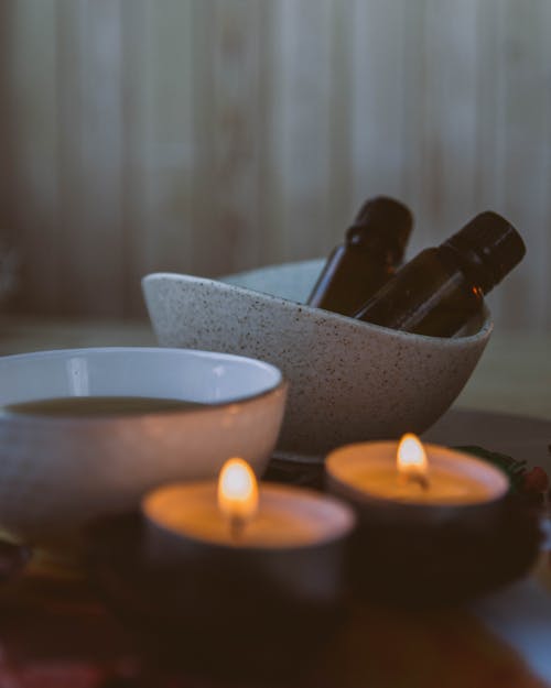 Close-Up View of Cosmetic Bottles in Bowl and Candles