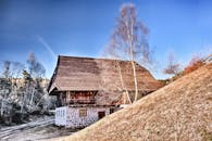 一座迷人的木制小屋，坐落在树木和丘陵环绕的寒冷冬季景观中