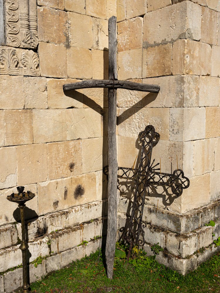 A Wooden And Metal Crosses Leaning Outside A Concrete Wall