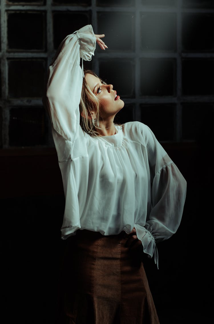 Blond Woman Standing In Ballet Pose With Arm Raised