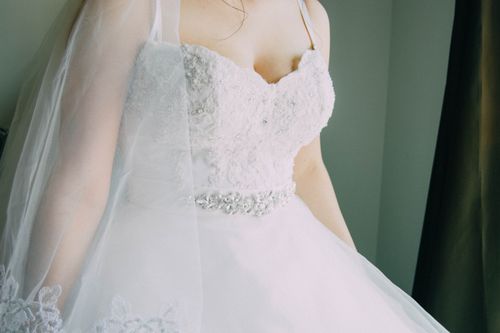 Free Detailed close-up of an elegant bridal gown with a sheer veil and intricate lace design. Stock Photo