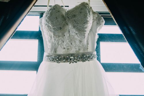 Free Close-up of an elegant bridal gown with lace detail hanging by a window. Stock Photo