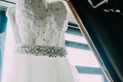 Free A close-up of an elegant lace wedding dress featuring intricate beading and a shimmering belt. Stock Photo