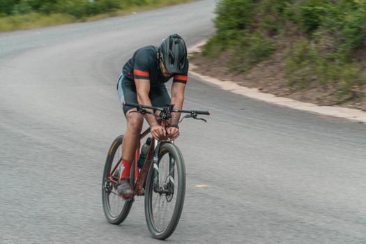 Cyclist racing on a mountain bike on a winding road during the day.