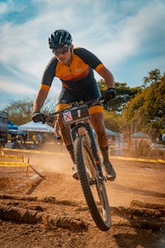 Energetic cyclist racing on a dusty trail with competition number during a mountain bike event.