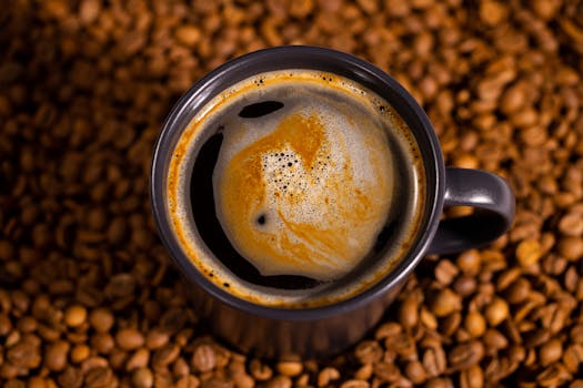 A rich espresso in a dark mug surrounded by roasted coffee beans, showcasing foam details.