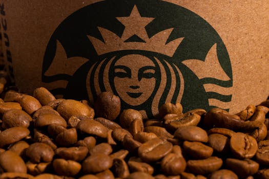 A detailed image of roasted coffee beans placed in front of a cardboard cup featuring a green logo.