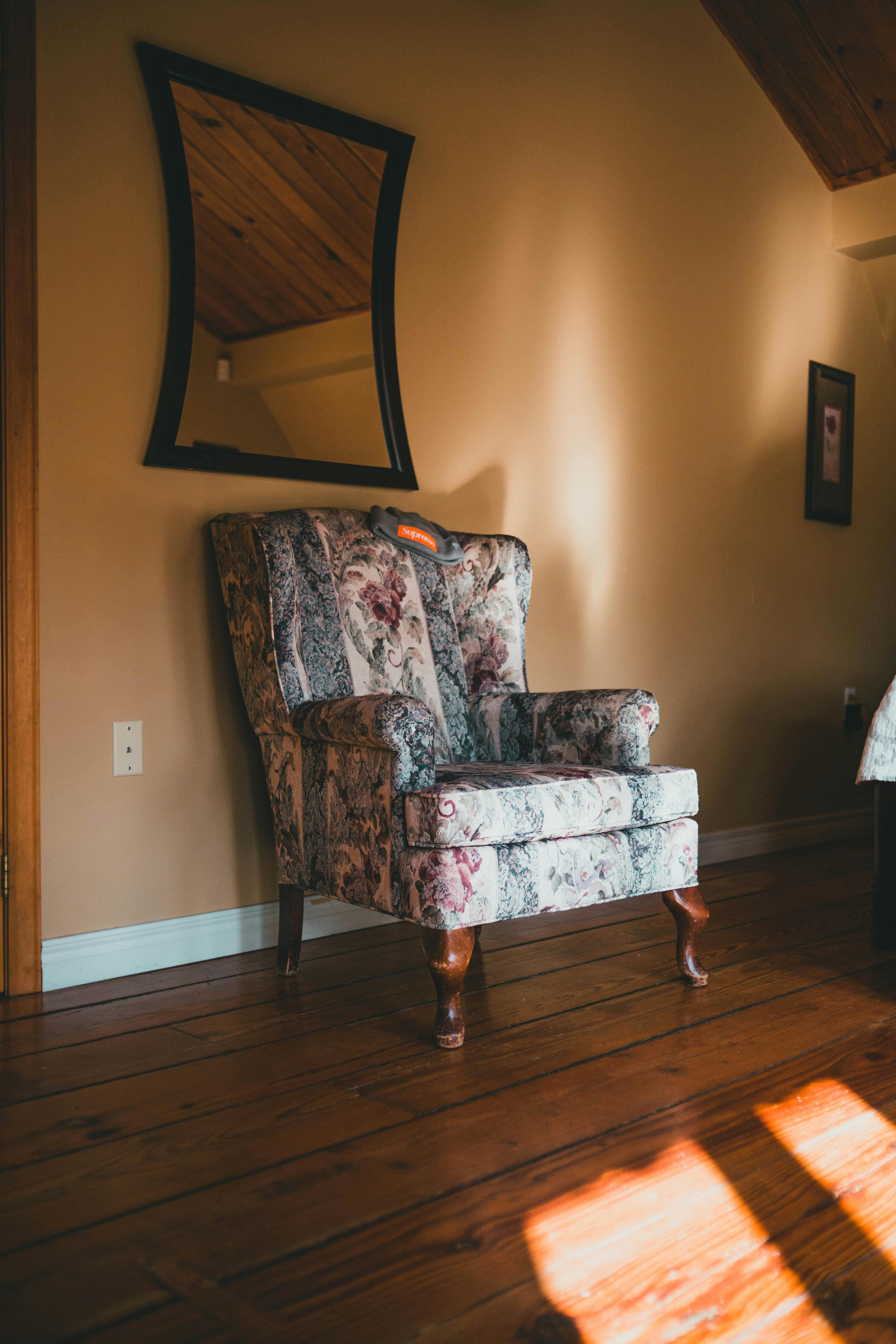 Free A floral armchair bathed in soft sunlight in a warm and inviting interior setting. Stock Photo