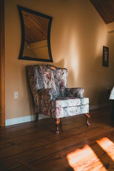A floral armchair bathed in soft sunlight in a warm and inviting interior setting.