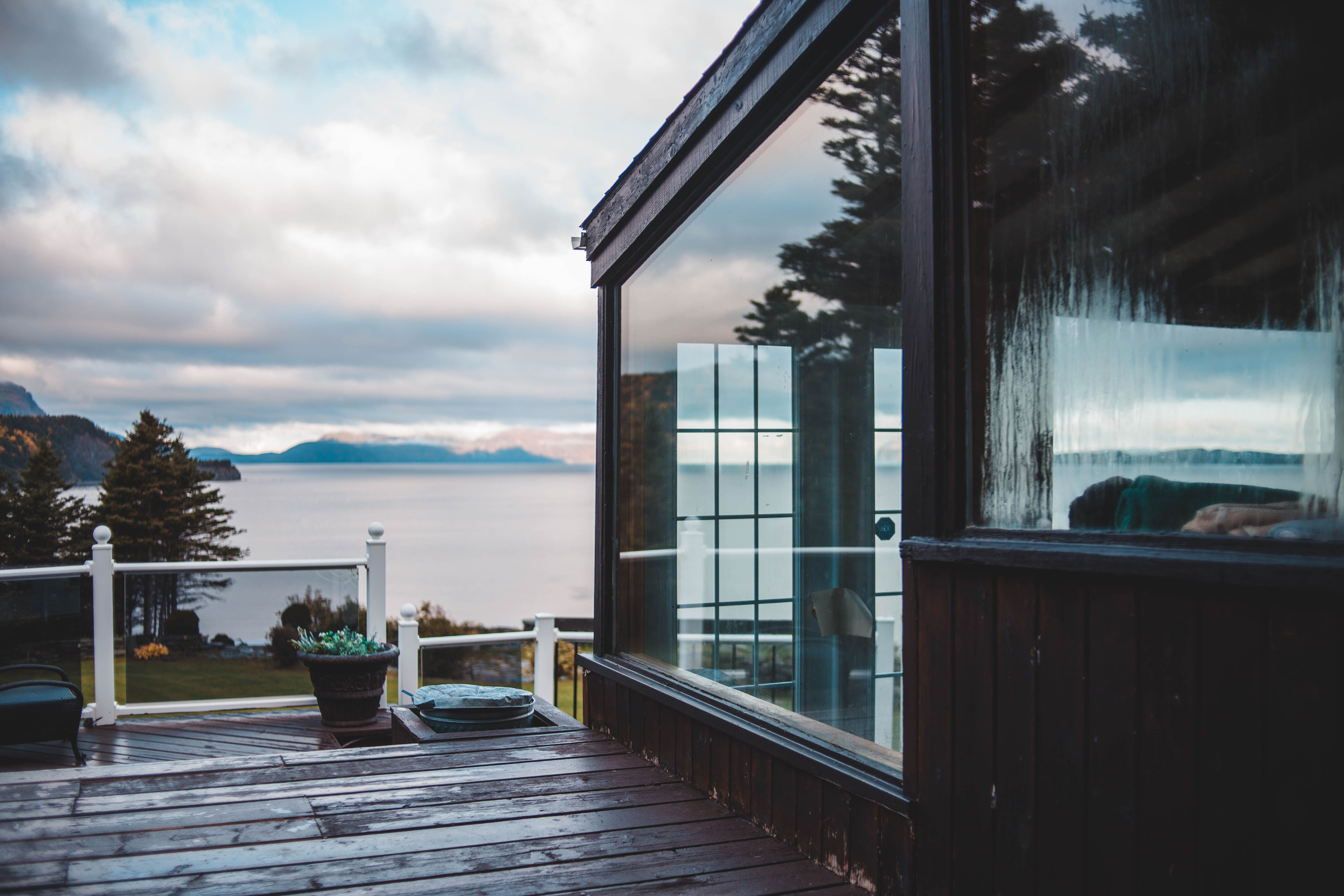 Beautiful lakeside view from a glass-walled terrace overlooking water and trees.