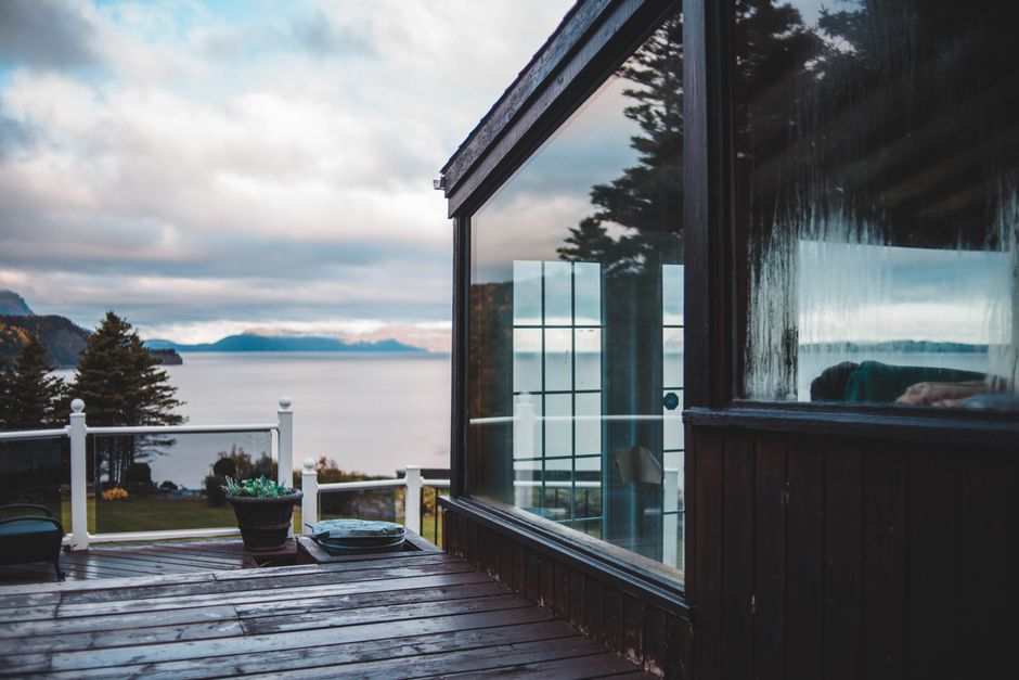 Photo by Erik Mclean on Pexels Beautiful lakeside view from a glass-walled terrace overlooking water and trees.