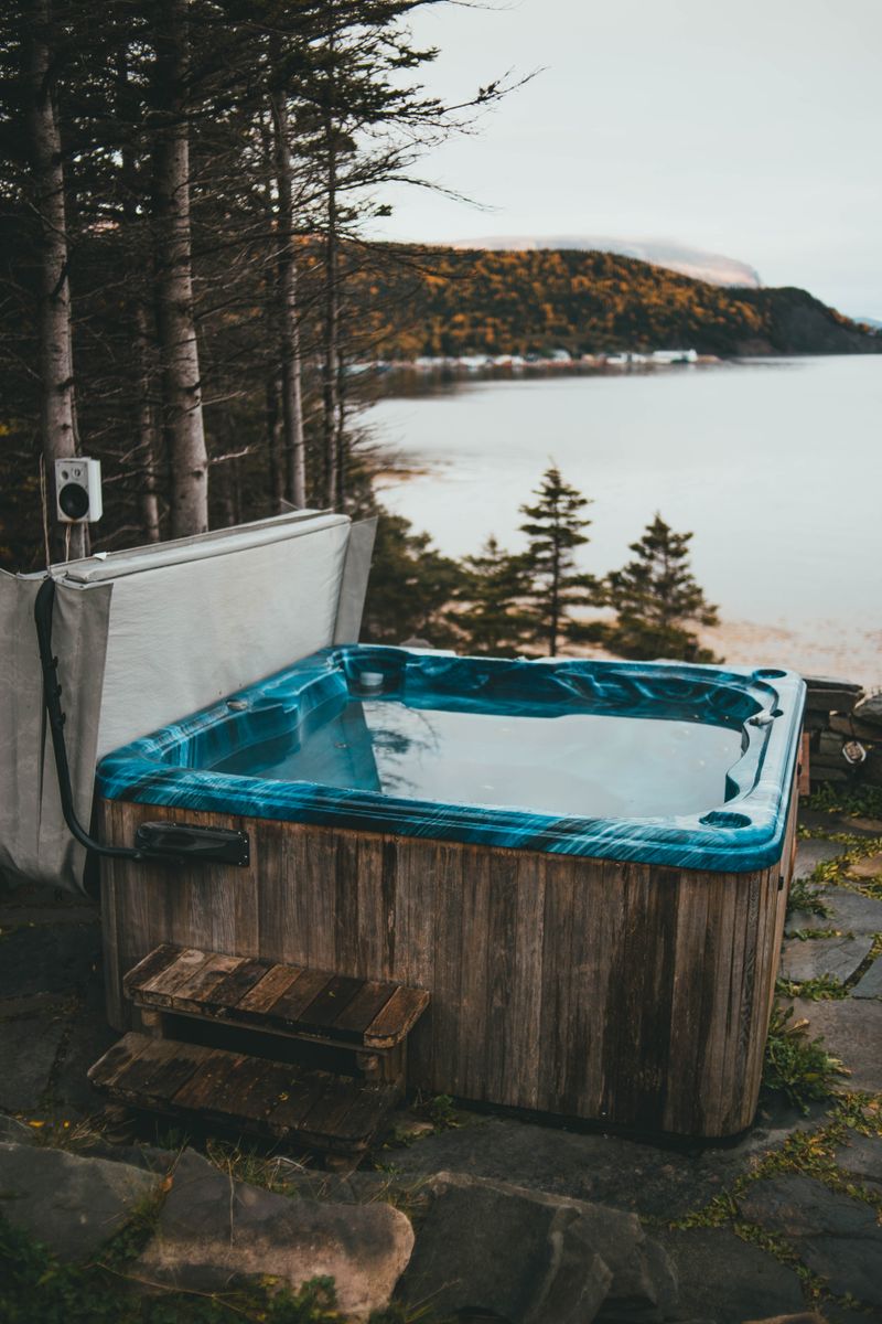 A cedar hot tub on a deck overlooking a lake