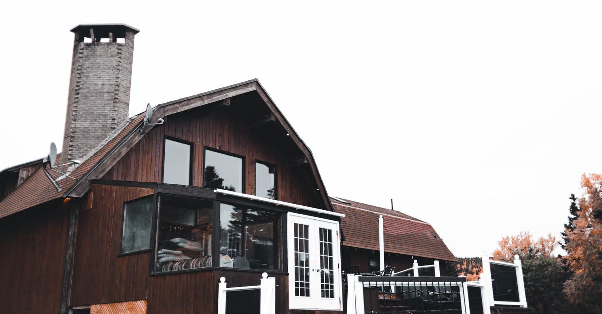 Charming wooden house exterior with chimney and spacious balcony in a serene outdoor setting.