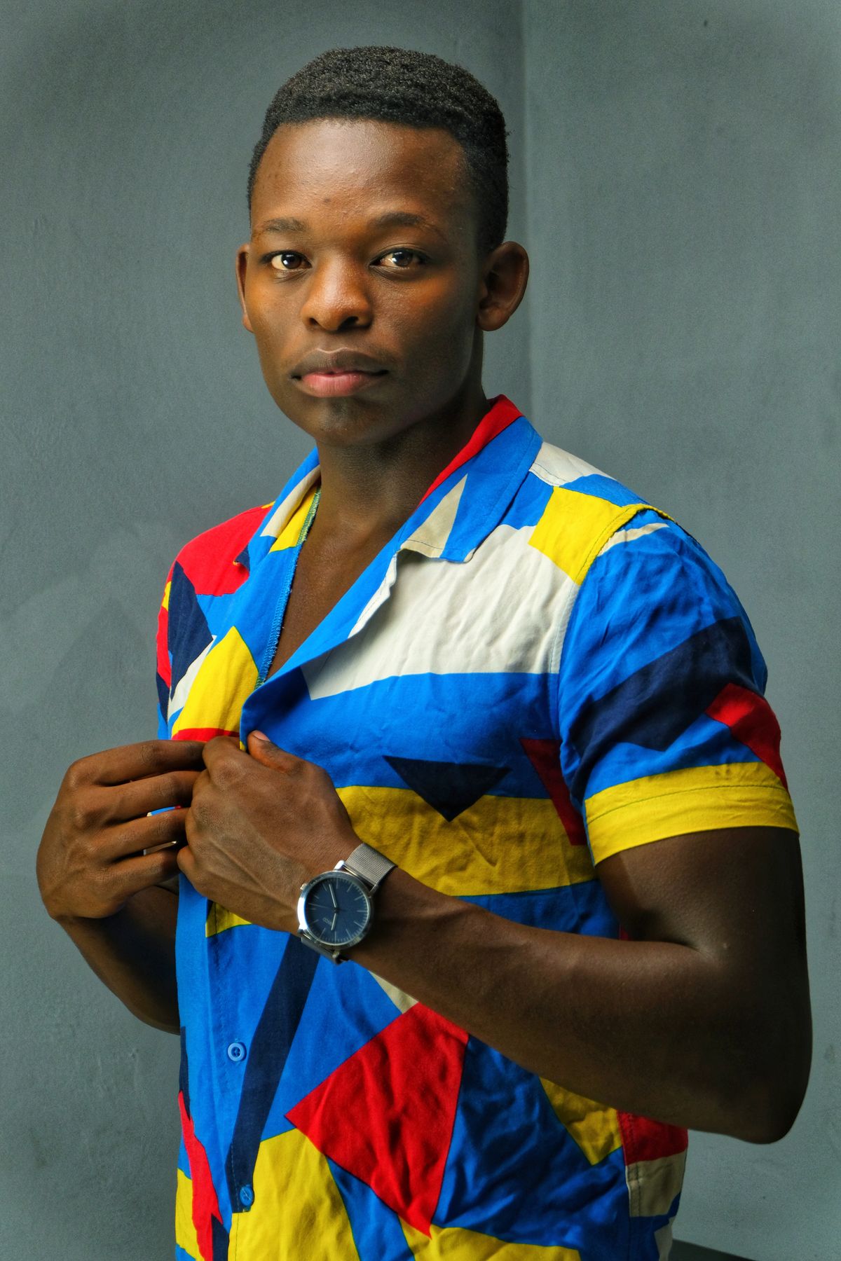 Homem em retrato editorial com camisa estampada de cores vibrantes em fundo neutro
