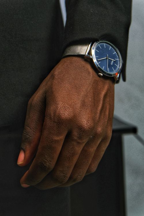 Free Stylish close-up of a black man's hand wearing an elegant silver wristwatch indoors. Stock Photo
