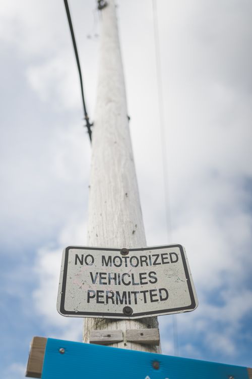 Free Low angle shot of a warning sign on a wooden pole against a cloudy sky. Stock Photo