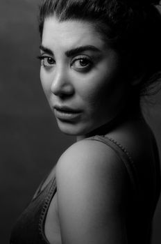 Grayscale portrait of a woman in a tank top, gazing thoughtfully.