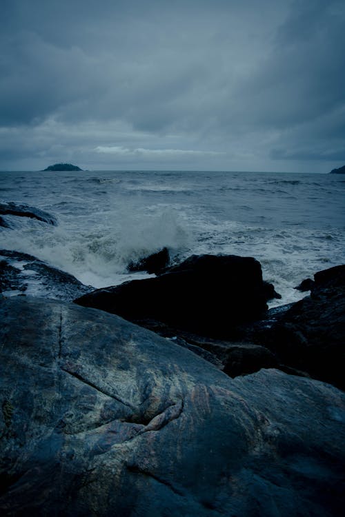 Ocean Waves Crashing on Rocky Shore Under Cloudy Sky