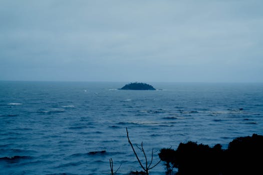A distant island seen over a calm sea, capturing tranquility and isolation.