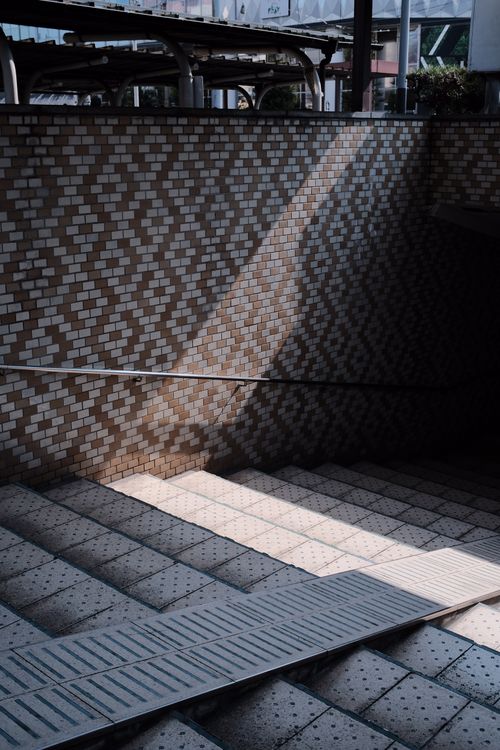 Free A sunlit subway entrance featuring a patterned tiled wall and stairs. Stock Photo
