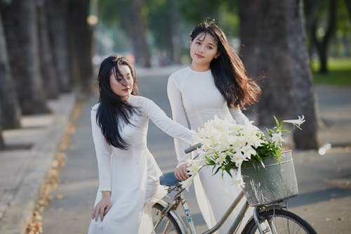 Women in White Dresses Posing Near a Bike