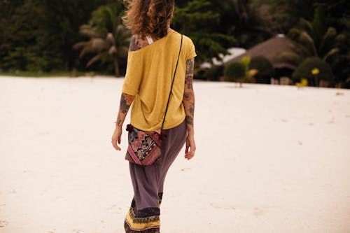 Woman Wearing Yellow Shirt Walking on White Sand