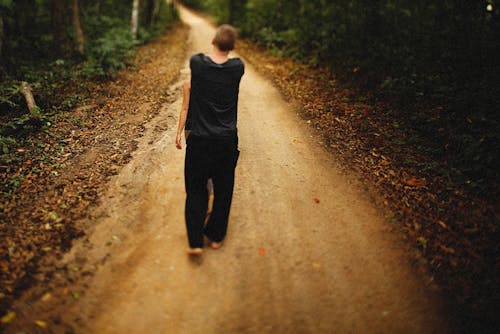 A Person Walking Barefoot on Unpaved Road