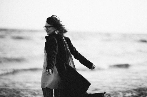Free Woman smiling in black and white, walking on a windy beach. Stock Photo