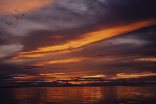 Captivating ocean sunset with vivid skies reflecting on tranquil water surface.