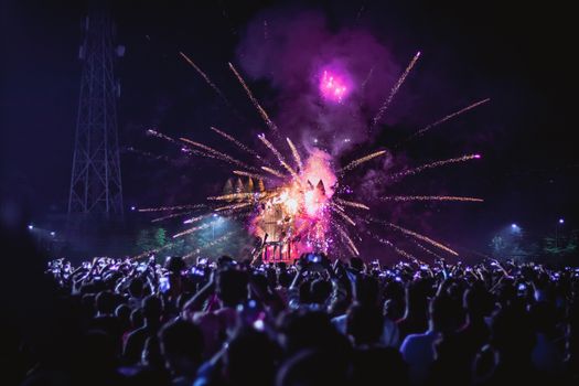 A colorful fireworks show illuminates the night sky, attracting a large crowd capturing the moment.