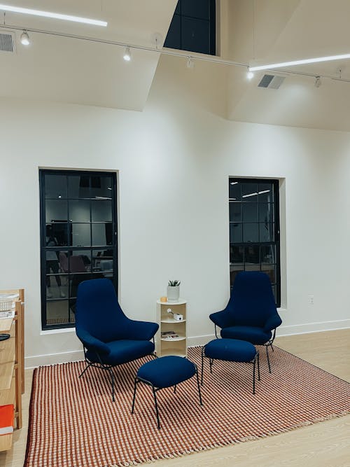 Blue Armchairs and Ottomans Near Glass Windows