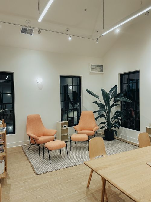 Free Minimalist interior with cozy orange chairs, indoor plant, and natural lighting creating a peaceful atmosphere. Stock Photo
