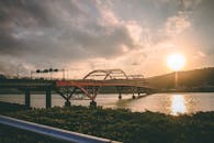 横跨河流的桥梁上，宁静的日落景色反射出温暖的色彩